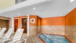 Ein Wellnessbereich mit Whirlpool, Liegestühlen und einer Tür zu Umkleideräumen.