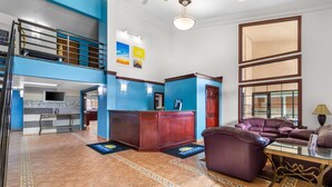 Eine geräumige Lobby mit einer Rezeption, einer Treppe und einer Sitzecke mit Ledersofas.