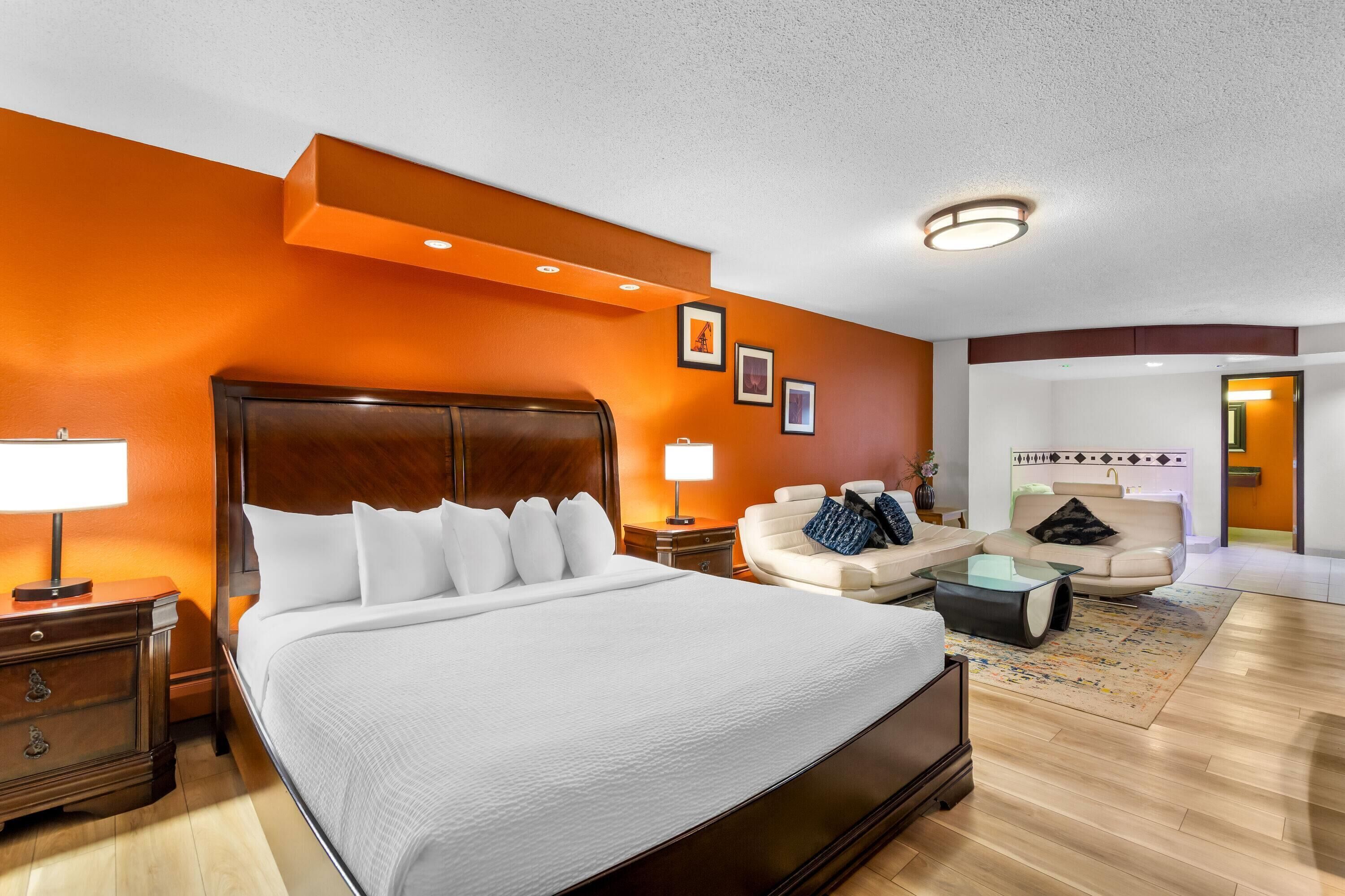 Una habitación de hotel con una cama grande, un sofá, una mesita de centro y una mesita de noche.