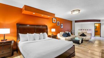 Una habitación de hotel con una cama grande, un sofá, una mesita de centro y una mesita de noche.