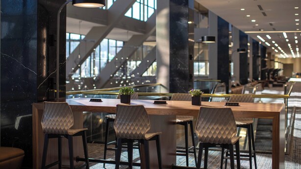 A modern conference room with a long table, four chairs, and potted plants. - Renaissance Dallas Addison Hotel (Addison)