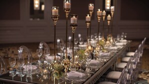 A long dining table set with clear glassware, white napkins, and candle holders. - Renaissance Dallas Addison Hotel (Addison)