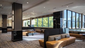 A spacious lobby with a large seating area, a marble column, and large windows offering a view of the outdoors. - Renaissance Dallas Addison Hotel (Addison)