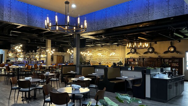 Un restaurant doté d'un bar, de différents types de tables et de chaises, et d'une enseigne au néon.