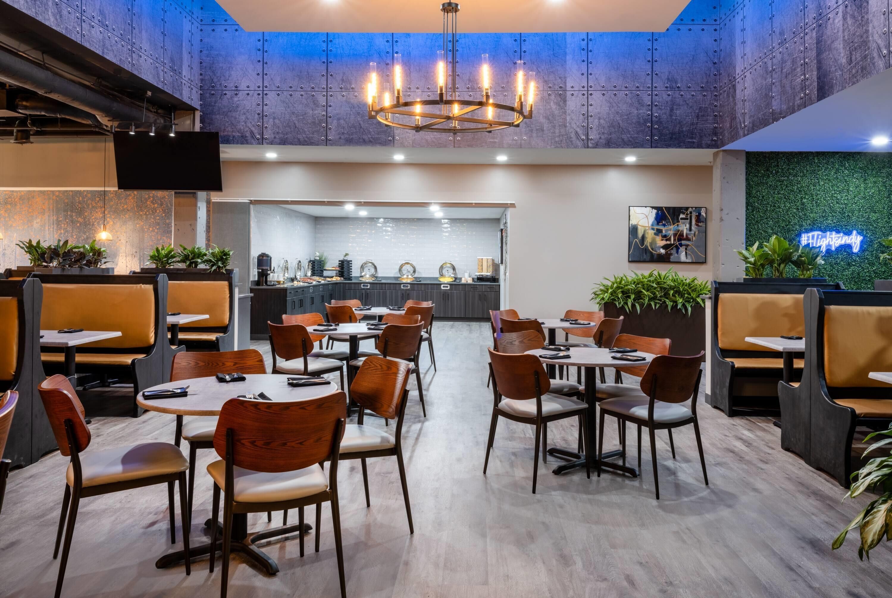 A modern restaurant with high ceilings, exposed ductwork, and a central bar area.