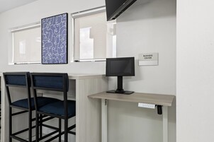 Un espacio de trabajo con dos sillas, un escritorio, un monitor de computadora y un letrero en la pared que dice 'BUSINESS CENTER'.