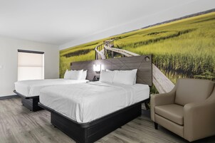 Habitación de hotel con una cama grande, una silla y un mural en la pared de un campo.