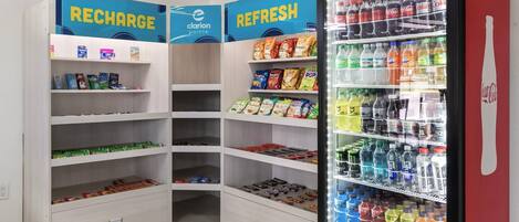 A corner of a store with shelves stocked with snacks, beverages, and a refrigerated display case.