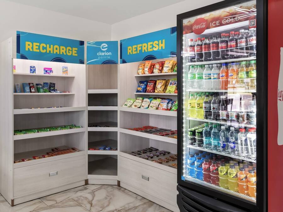A corner of a store with shelves stocked with snacks, beverages, and a refrigerated display case.