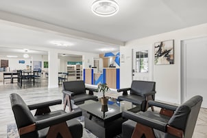 Un espacio de oficina moderno con mostrador de recepción, área de descanso y kitchenette.