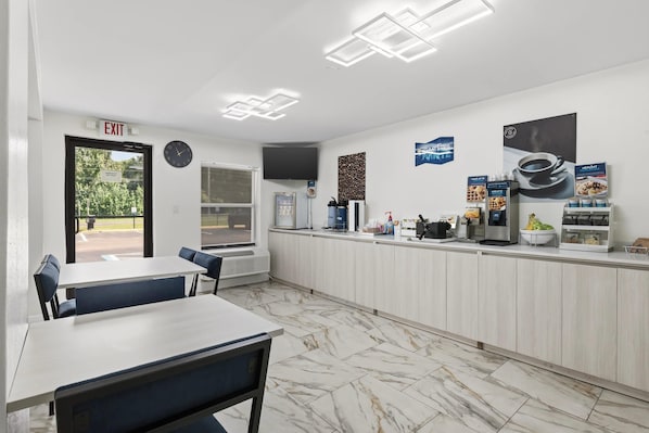 A clean, modern cafe with a marble floor, a counter with coffee machines, and a clock on the wall. - Clarion Pointe Alachua - Gainesville Area (Alachua)