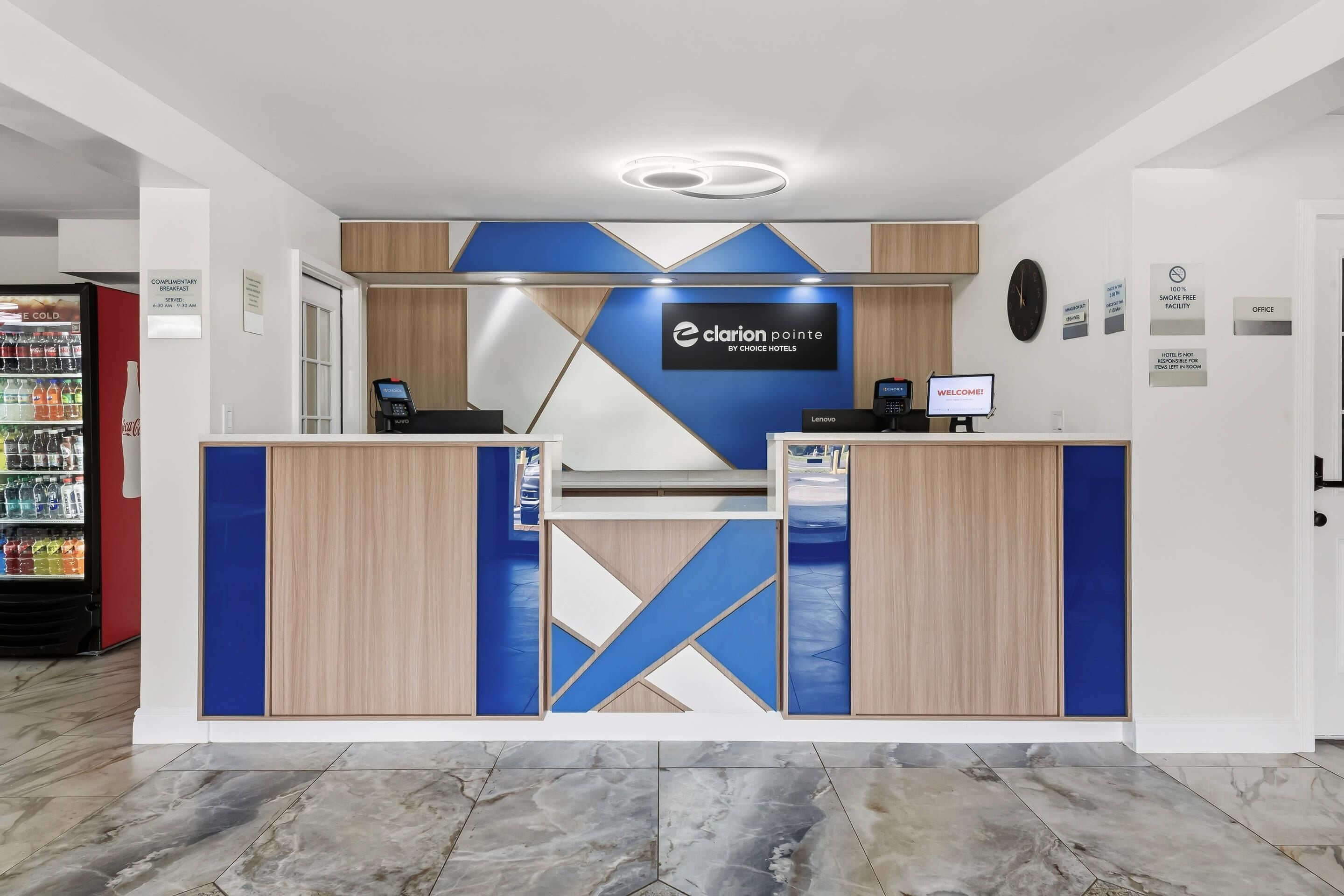 Ein moderner Hotelrezeptionstresen mit einer Uhr und einem Willkommensschild.