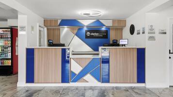 Ein moderner Hotelrezeptionstresen mit einer Uhr und einem Willkommensschild.