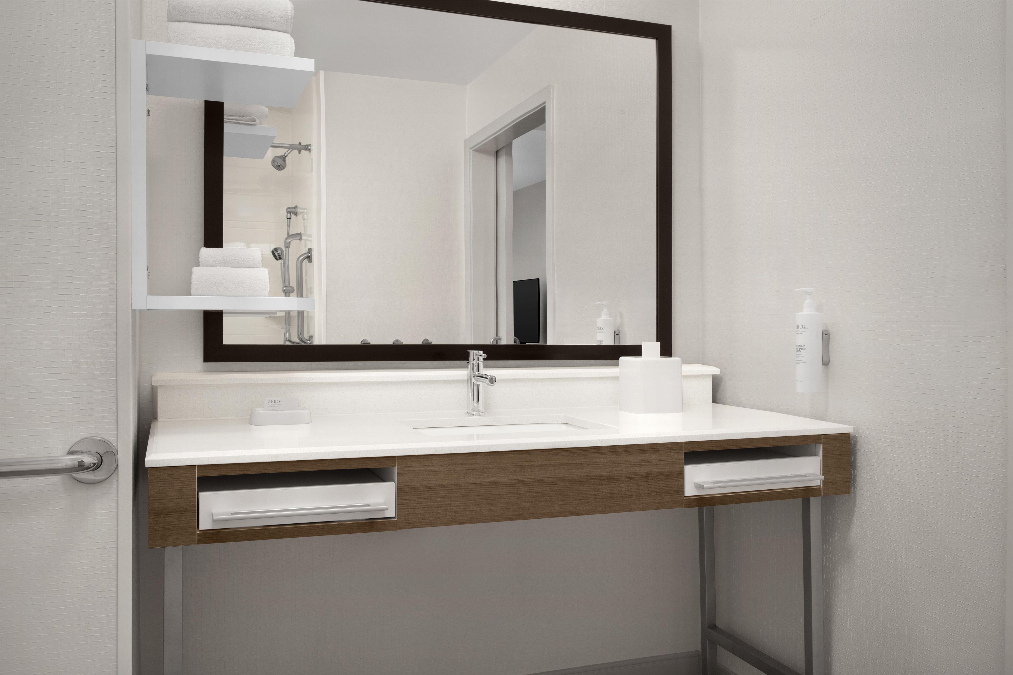 Une salle de bain moderne avec un lavabo blanc, un miroir à cadre noir et un porte-serviettes.