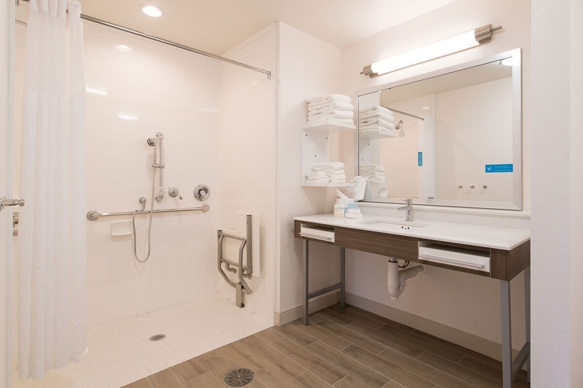 Un baño moderno con cabina de ducha de vidrio, tocador con espejo y toallero.