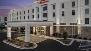 Ein Hampton Inn Suites Hotel mit moderner Fassade, überdachter Einfahrt und Parkplatz.