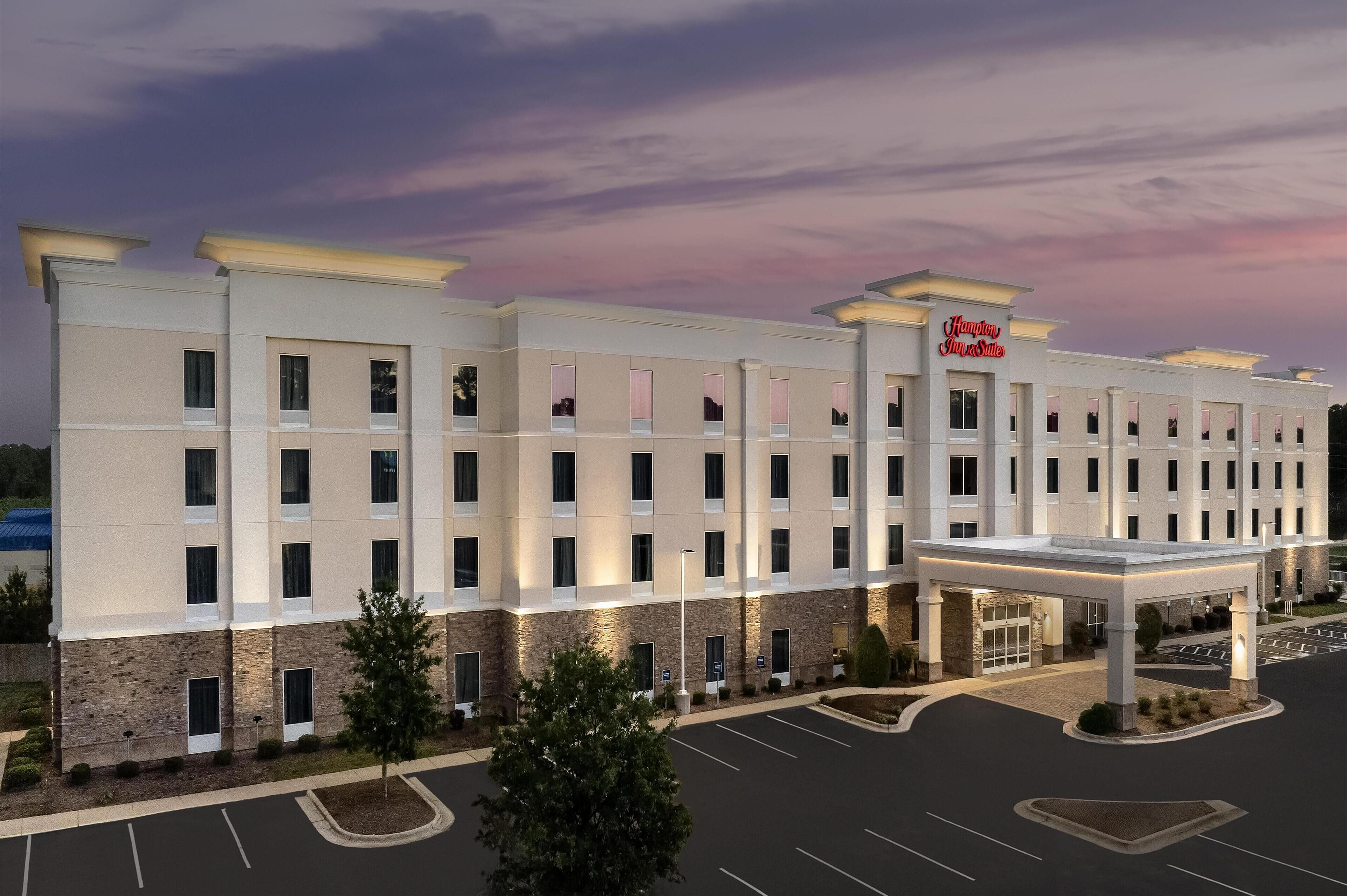 A Hampton Inn & Suites hotel with a modern facade, multiple floors, and a covered entrance.