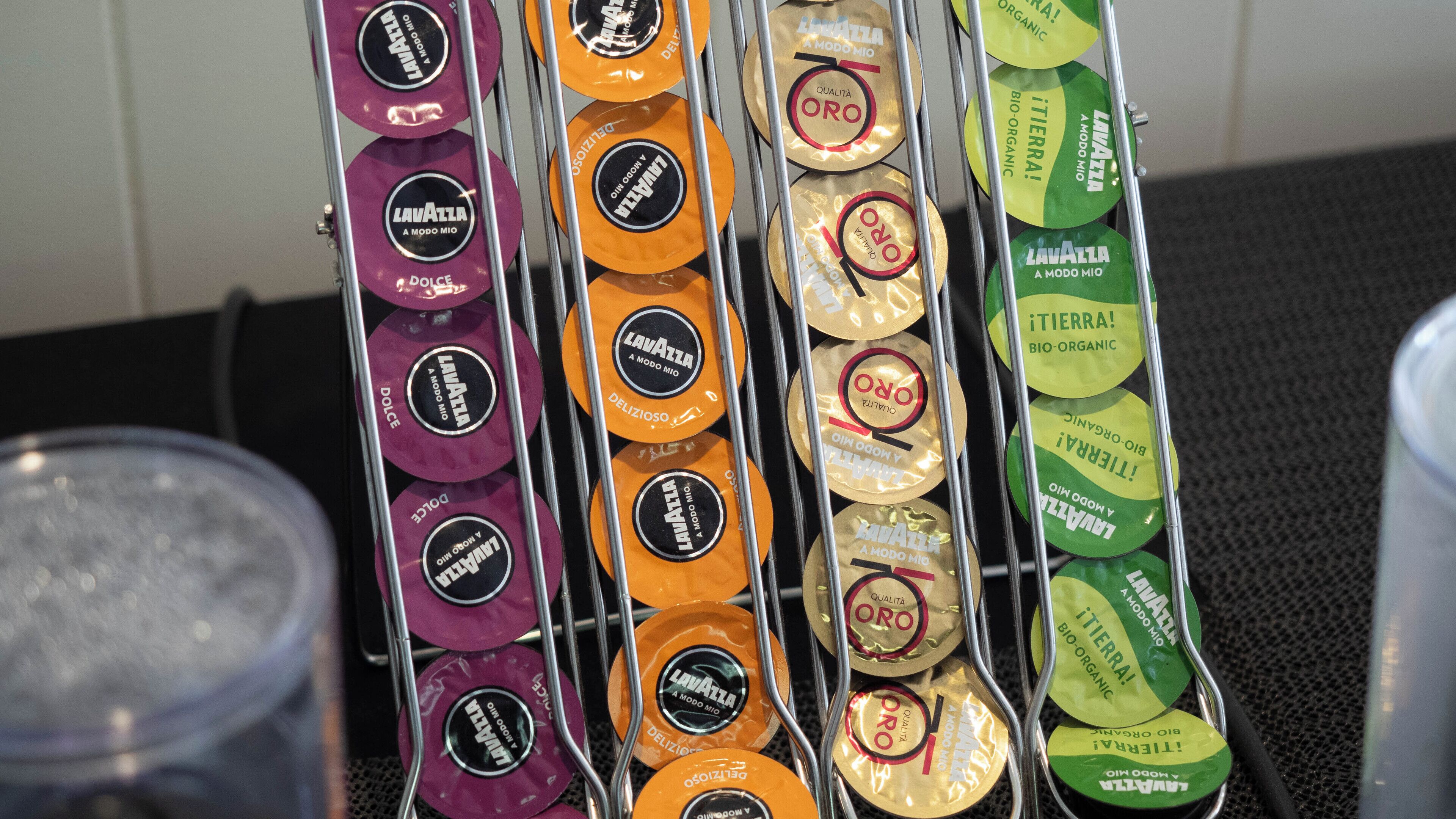 Una exhibición de ruedas de queso en varios colores, cada una etiquetada con 'Lavazza' y 'A Modo Mio'.
