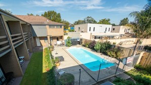A residential area with a swimming pool, a fenced patio, and a view of neighboring houses.