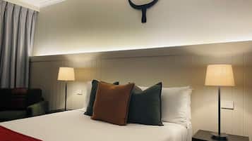Een hotelkamer met een bed, twee bedlampen, een hoofdbord met een decoratieve hoorn en een rode plaid.