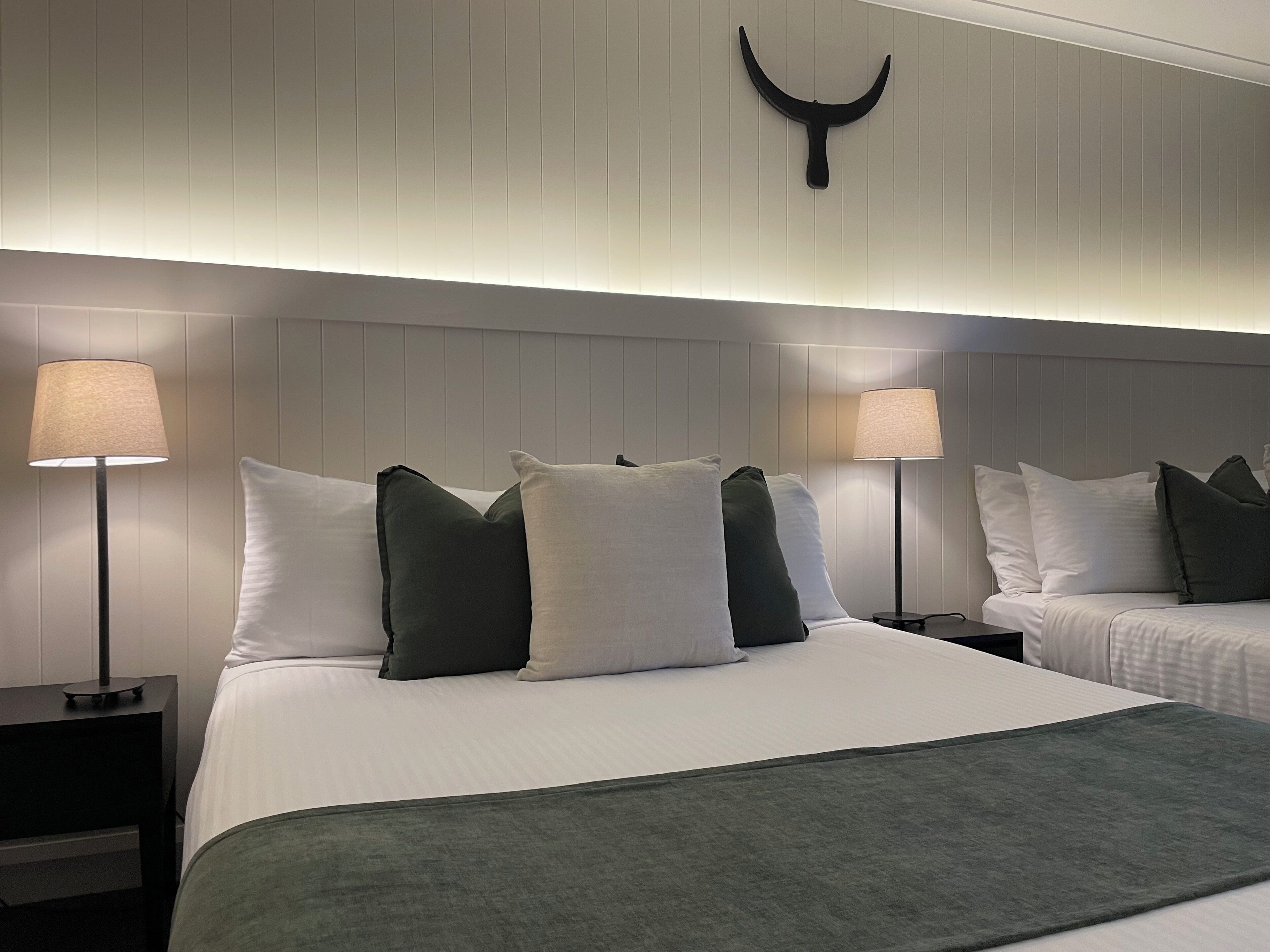 Camera d'albergo con un letto grande, due comodini, un lampadario a parete e un elemento decorativo a parete.