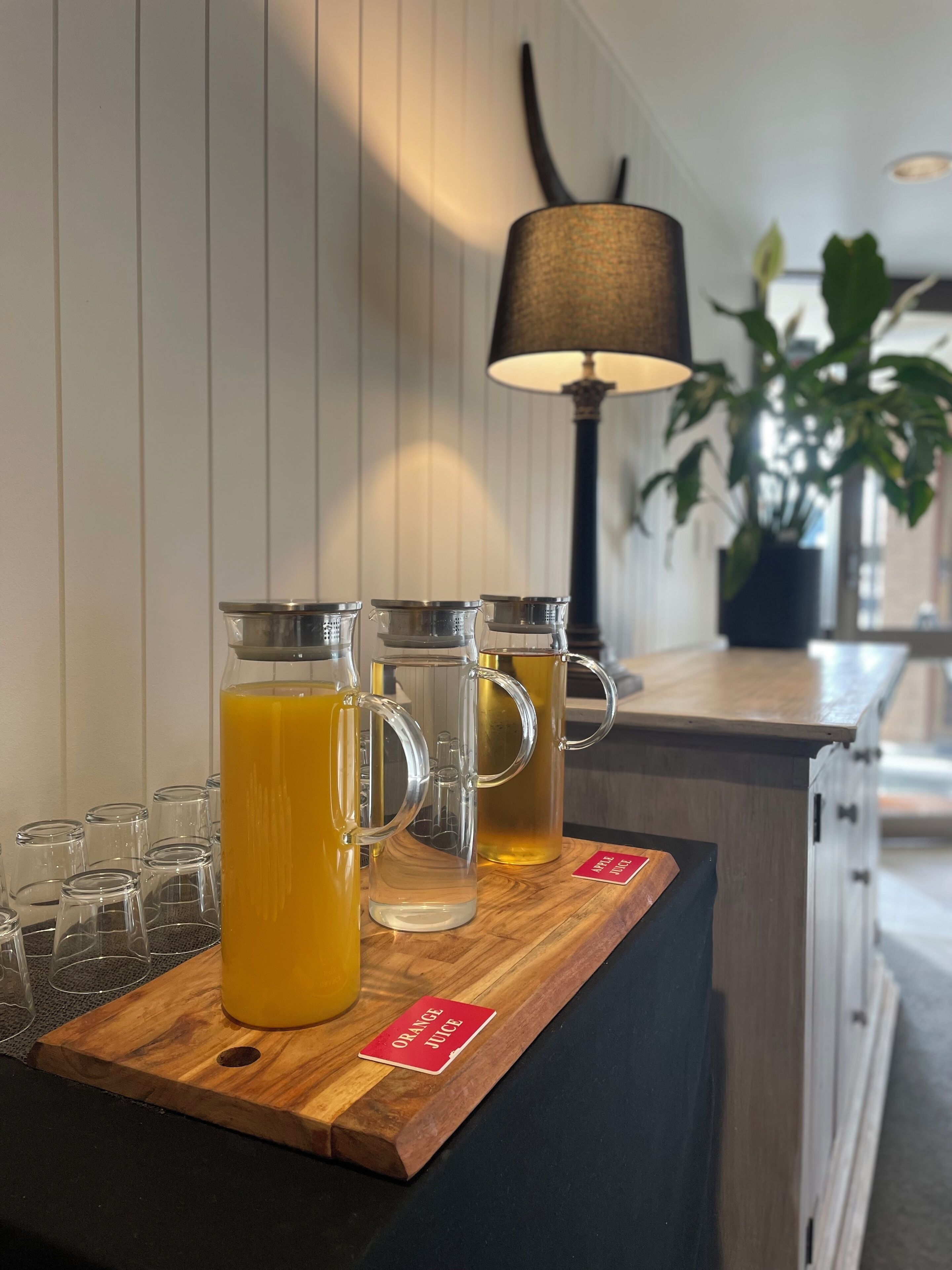 En trædisk med en bakke, der indeholder to glas med appelsinjuice og adskillige tomme glas.