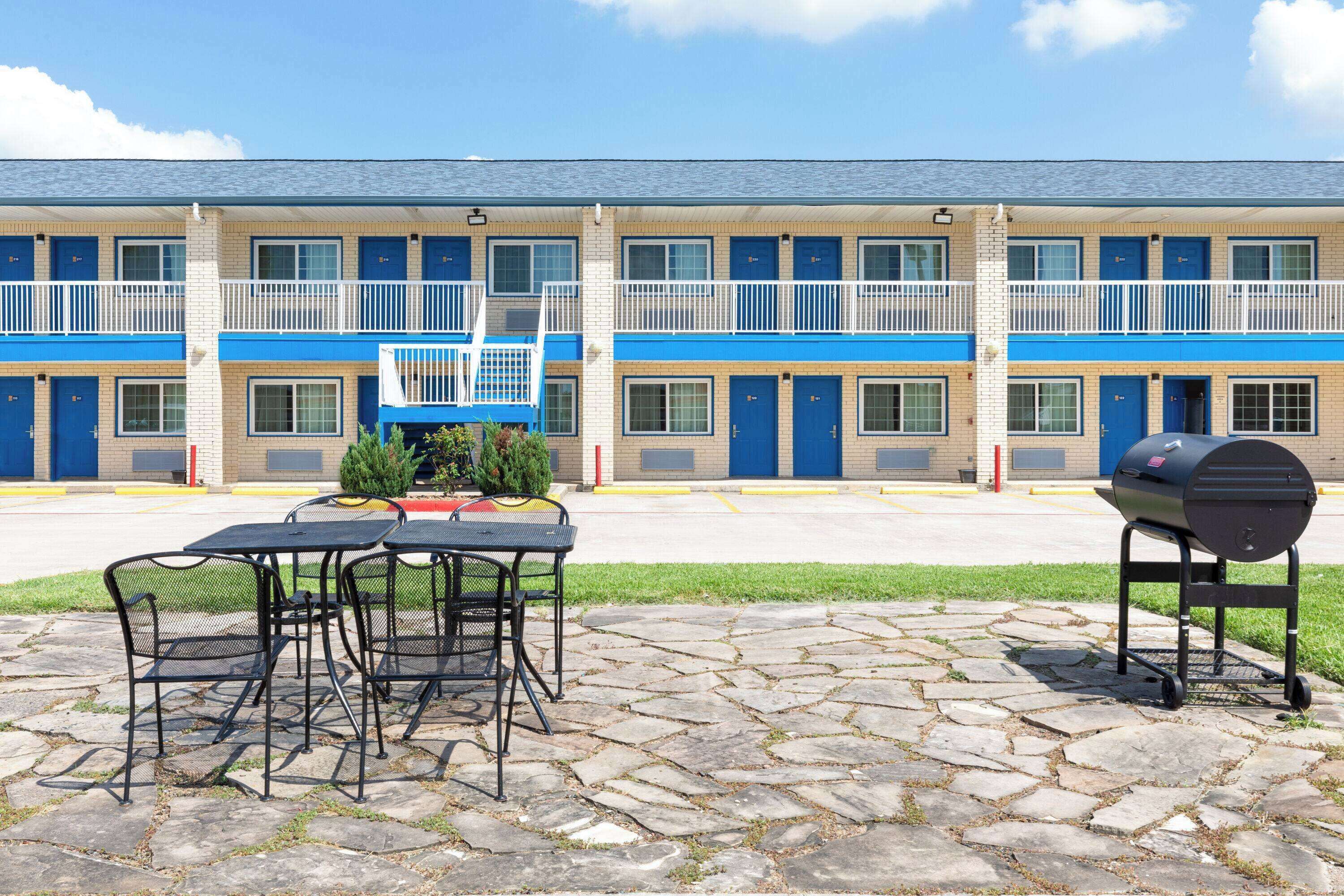 A motel with a two-story structure, outdoor seating area, and a barbecue grill.
