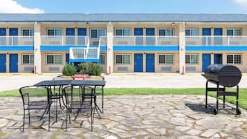 A motel with a two-story structure, outdoor seating area, and a barbecue grill.