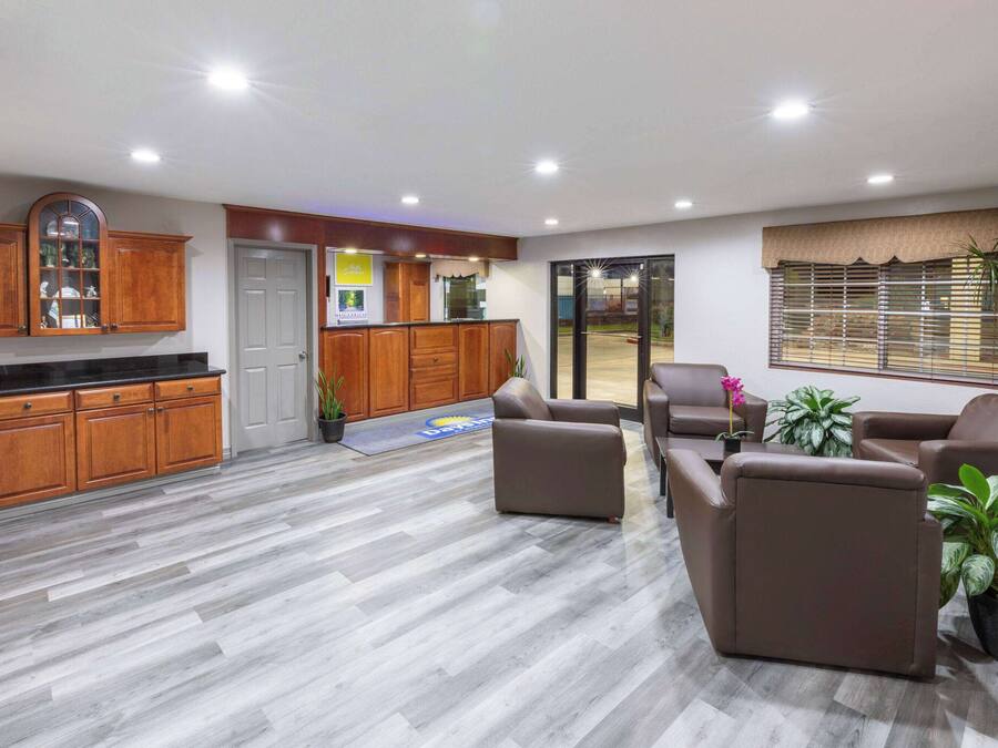 Una cocina moderna con armarios de madera y encimera negra. Hay una zona de estar con sofás de cuero marrón y una mesa de comedor.