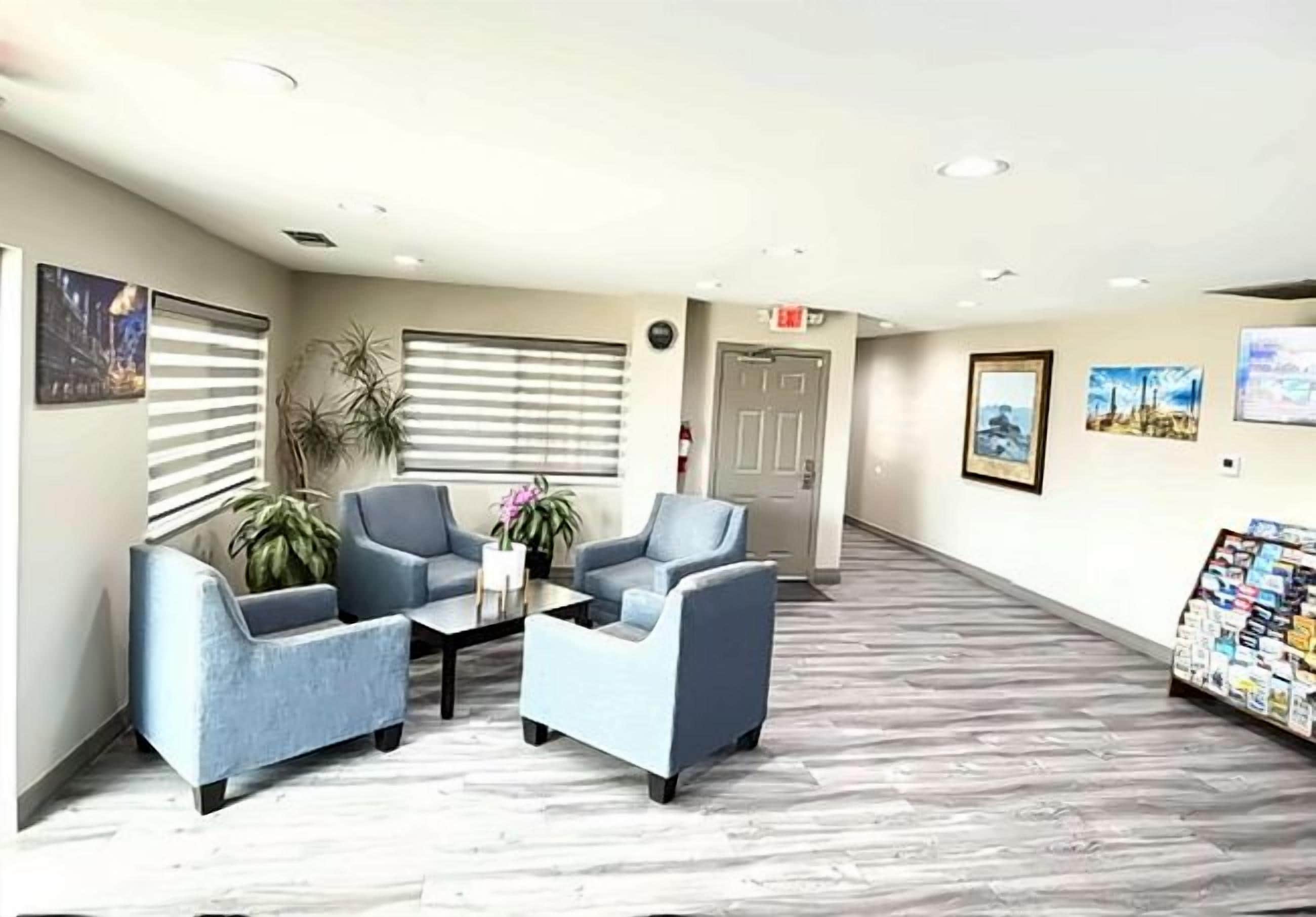 A reception area with a reception desk, two blue armchairs, a coffee table, and a plant.