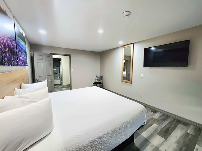 Habitació d'hotel amb un llit gran, un televisor de pantalla plana penjat a la paret i un mirall.