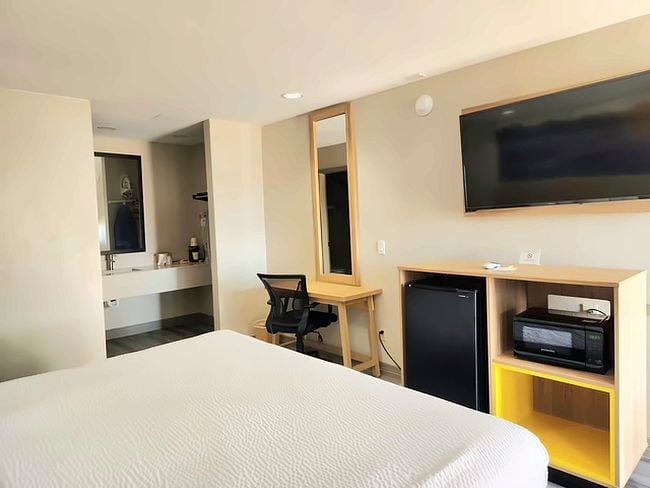 Une chambre d’hôtel équipée d’un lit, d’un bureau, d’une télévision et d’un mini-bar.
