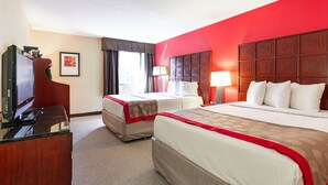 A hotel room with two beds, a TV, a desk, and a window with curtains. - Ramada by Wyndham Columbus North (Columbus)
