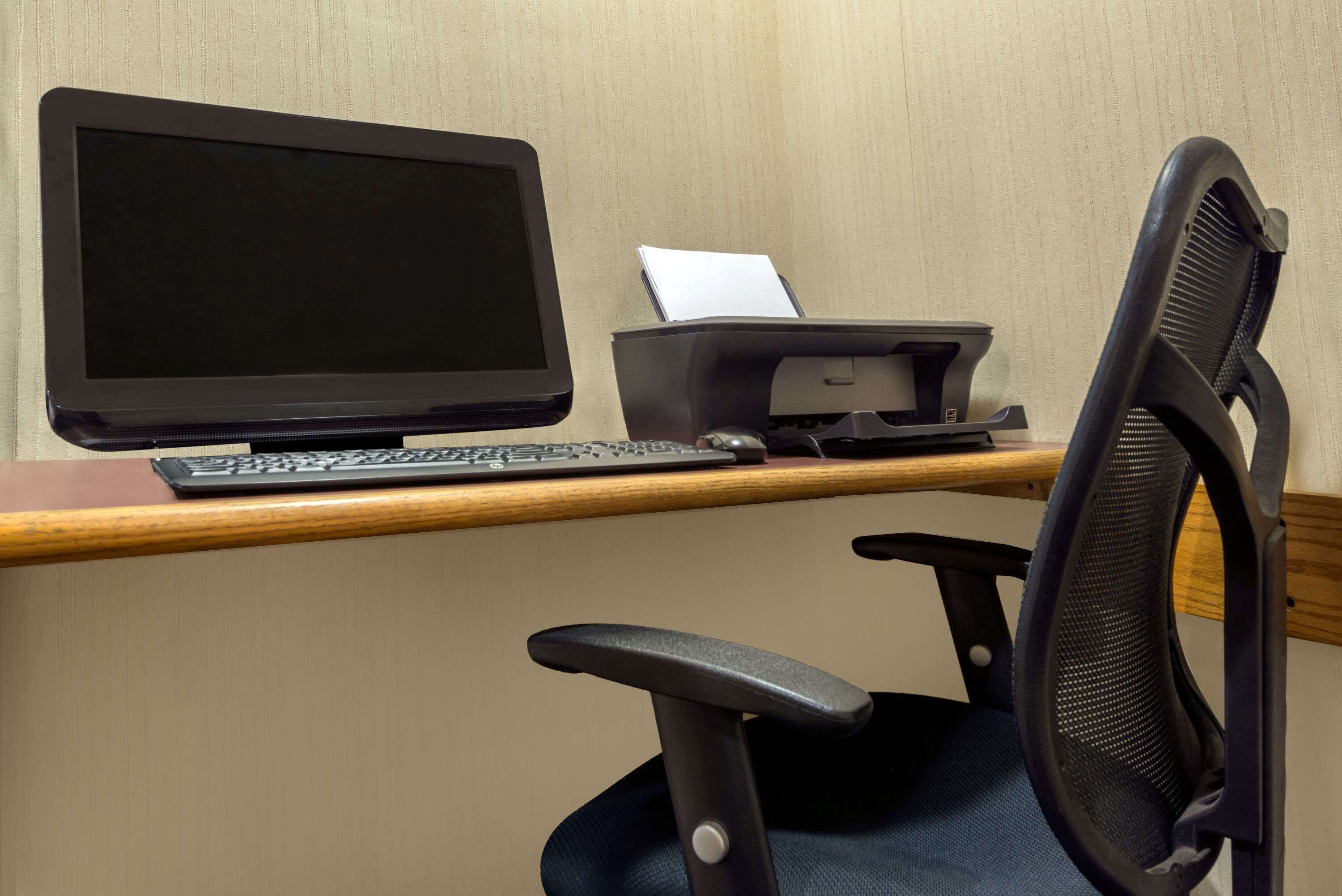 A computer desk with a monitor, keyboard, and printer.