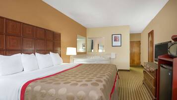 A hotel room with a large bed, a dresser, a television, and a bathroom visible in the background.