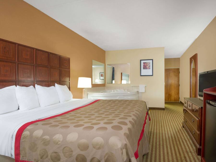 A hotel room with a large bed, a dresser, a television, and a bathroom visible in the background.