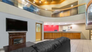 A modern lobby with a flat-screen TV, a reception desk, and a leather sofa. - Ramada by Wyndham Columbus North (Columbus)