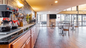 A modern bar area with a coffee machine, seating, and a large window. - Ramada by Wyndham Columbus North (Columbus)