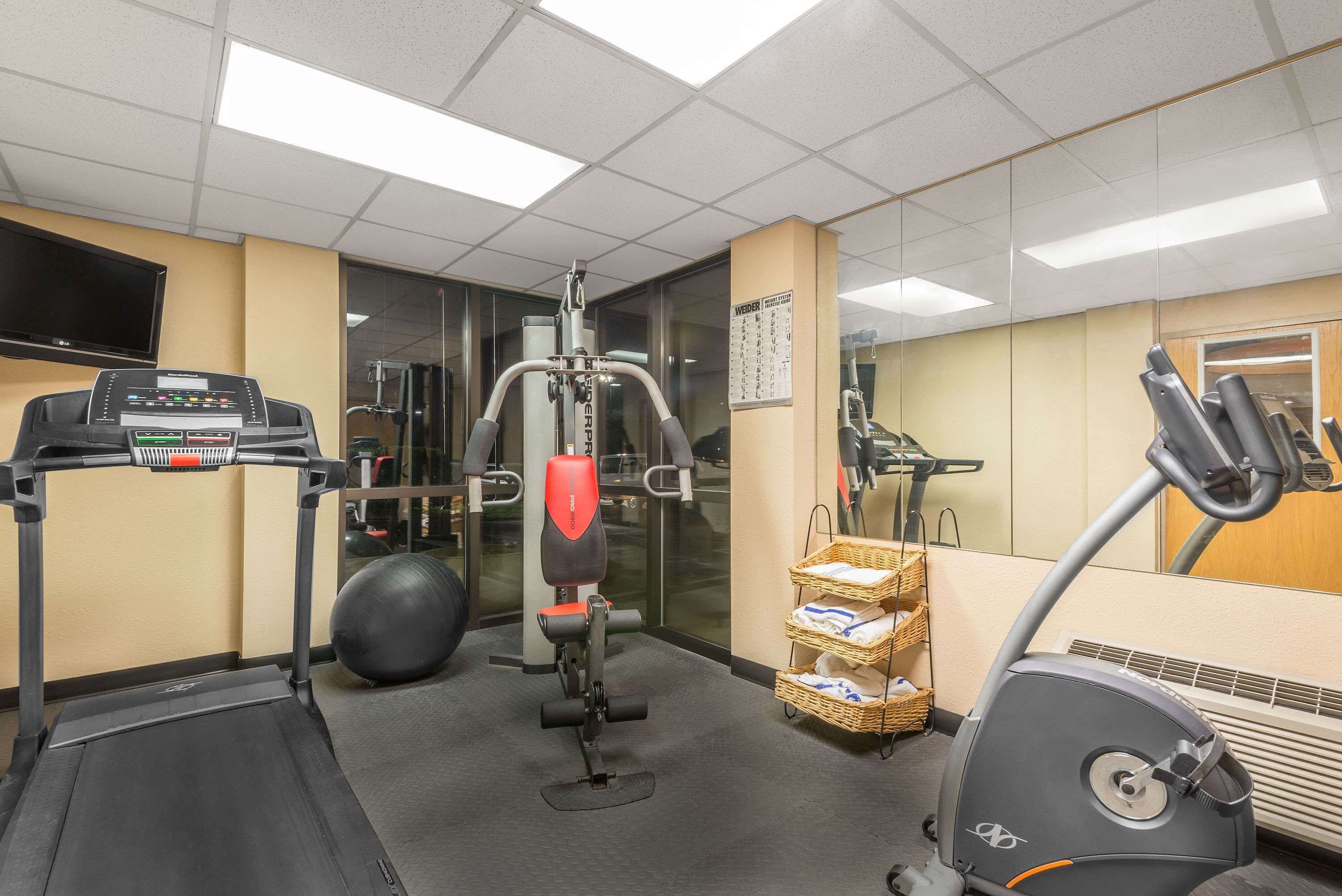 Een fitnessruimte met een loopband, krachtapparaat, fitnessbal en elliptische trainer.