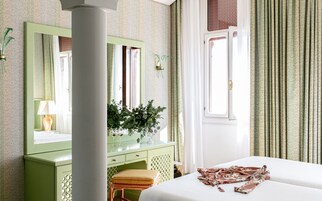 A bedroom with a bed, a dresser, a mirror, and a window with curtains.