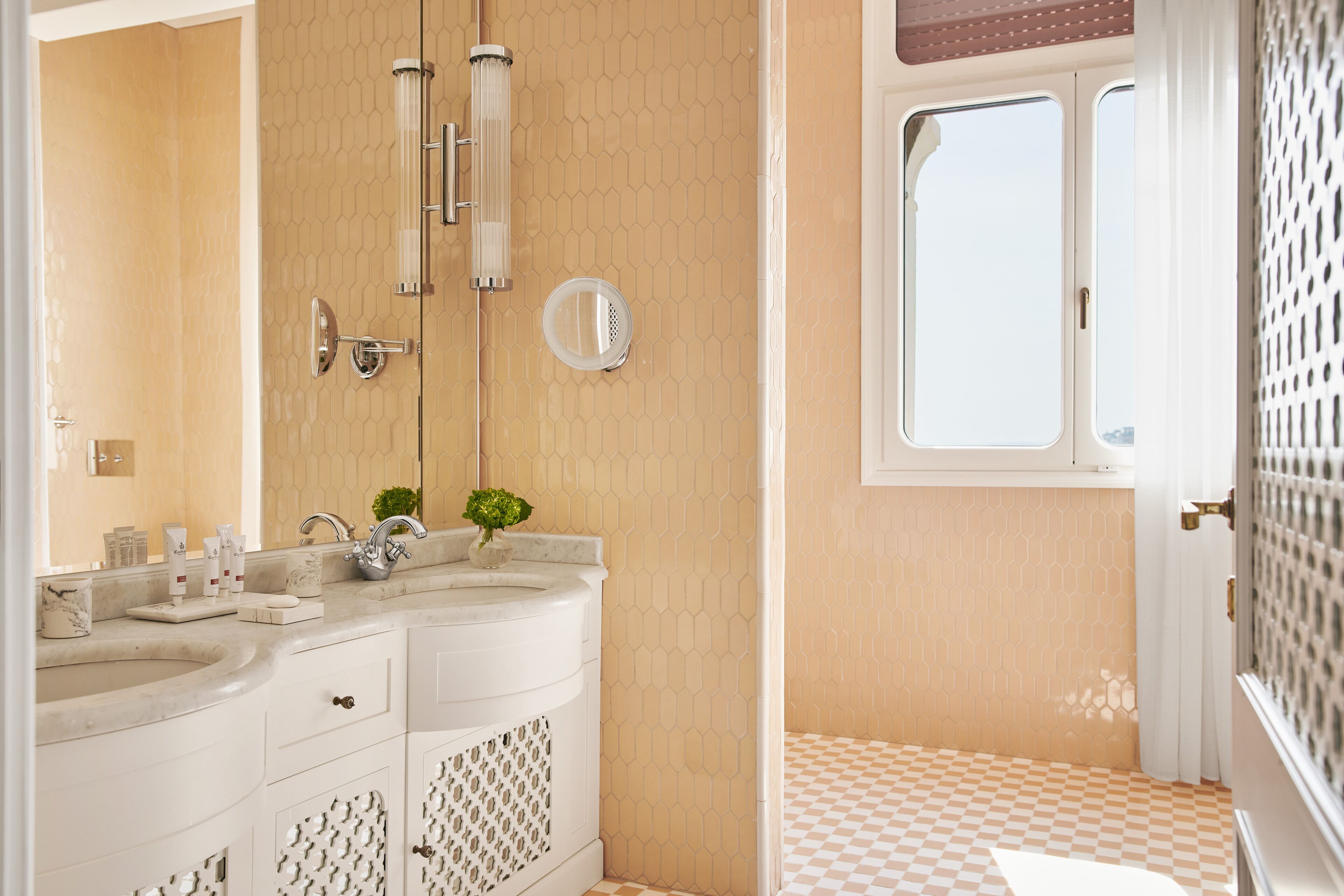 Une salle de bain avec un double lavabo, un miroir et une fenêtre.