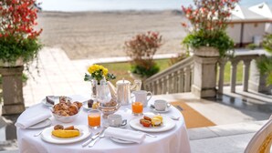 A breakfast table with various dishes, a pitcher of orange juice, and a view of the beach. - Hotel Excelsior Venice (Venice)