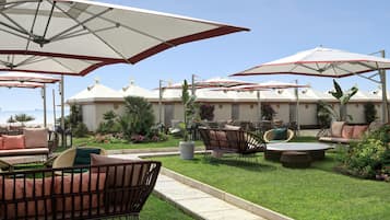 A patio area with outdoor furniture, umbrellas, and a well-maintained lawn.