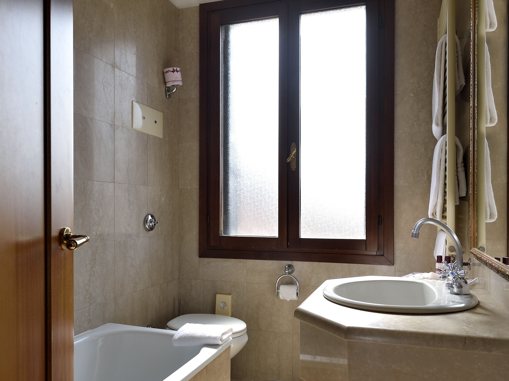 Ein Badezimmer mit Badewanne, Waschbecken, Toilette und einem Fenster.