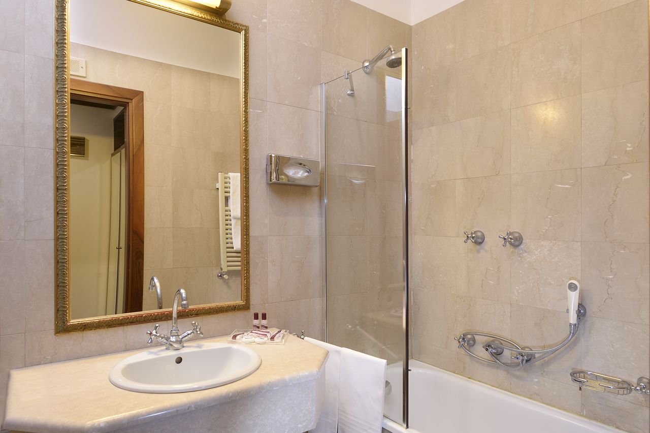 Een badkamer met wastafel, spiegel, douche en bad.