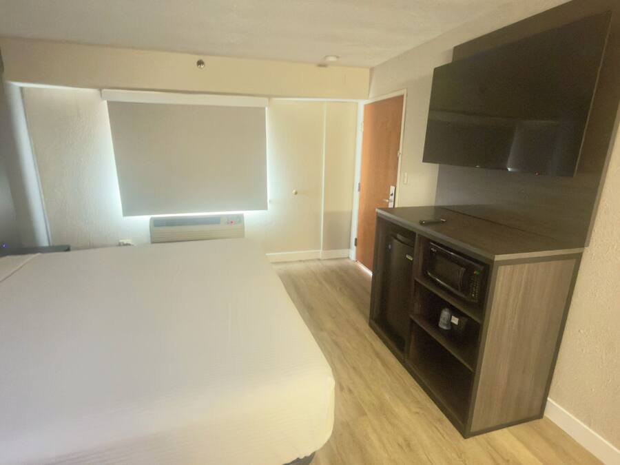 Une chambre d’hôtel équipée d’un lit, d’une télévision, d’un four à micro-ondes et d’une armoire.