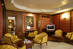Ein Zimmer mit Fernseher, Schreibtisch mit Computer und mehreren Stühlen.