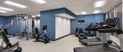 A gym with treadmills, elliptical machines, and weightlifting equipment.