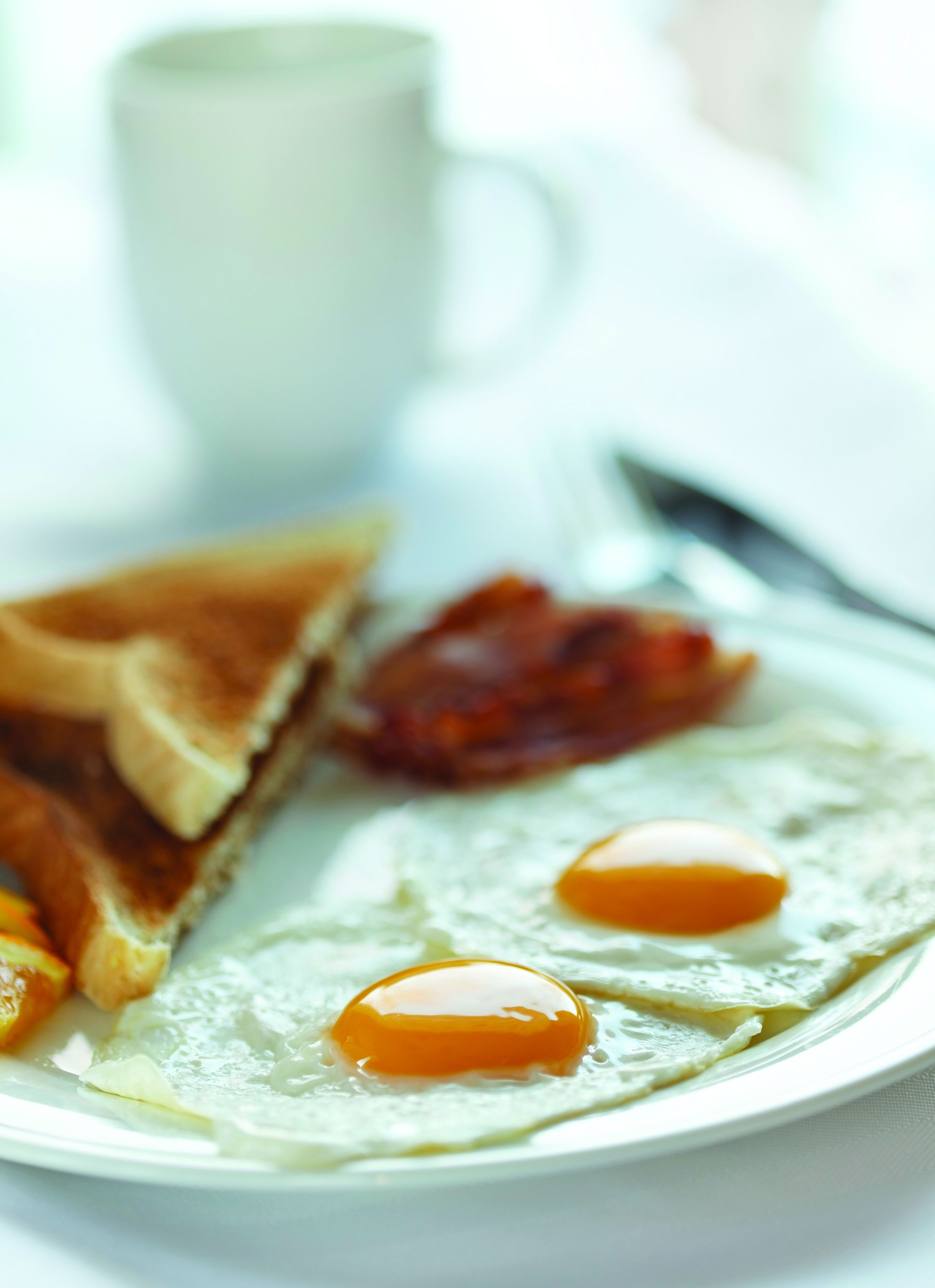 A breakfast plate with toast, bacon, and two fried eggs.