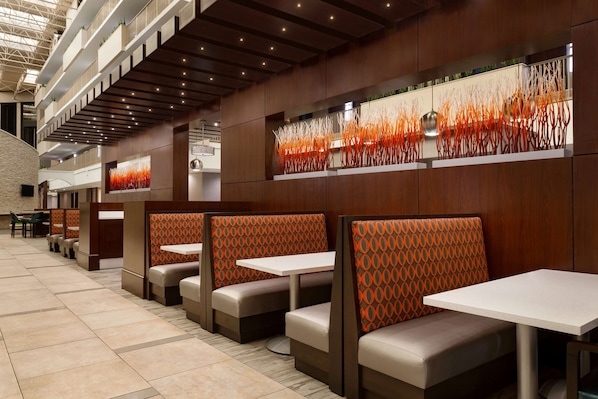 Un restaurante moderno con asientos tipo cabina, techos altos y una pared decorativa.
